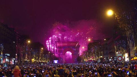 PARIS, FRANCE - DECEMBER, 31. Beautiful New year fireworks above famous triumphal arch, Arc de Triomphe. Tourists shooting videos and photos with their mobile phones. 4K clip