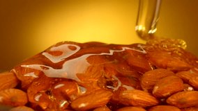 Honey pouring on almond nuts over yellow background. 4K UHD video footage. Ultra high definition 3840X2160