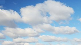 Footage loop features puffy clouds moving along a beautiful gradient blue sky on a bright, sunny day.