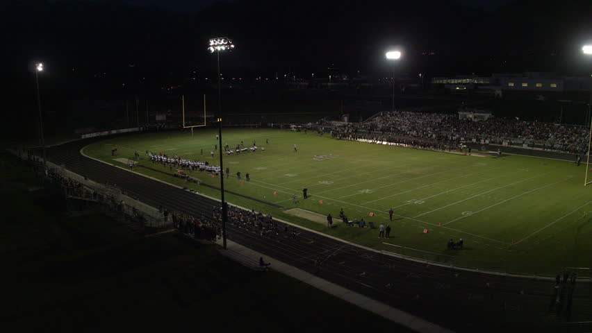 High school football game establishing aerial shot at night under the lights. September 2016