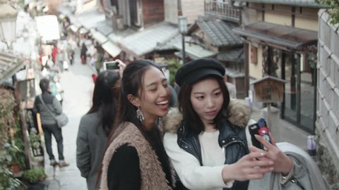 International friends take selfie in Kyoto old street. Two friends take photos on Famous Japanese Street in Kyoto. 