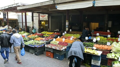 ATHENS, GREECE - CIRCA 2016: Panning over romantic market with customers buy choosing fresh vegetables, olives, tomatoes and organic vegetables and fruits at the Athens Central Market 