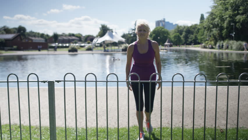 4K Healthy & active mature lady running in the park stops to do some stretches Dec 2016-UK