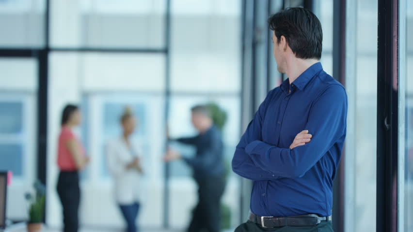 4K Portrait smiling casual businessman with coworkers standing in background Dec 2016-UK
