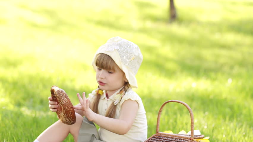 Girl eating bread and sitting in the meadow