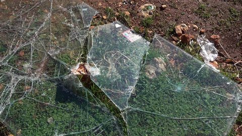 4K Glass broken to pieces against a stone on the ground
