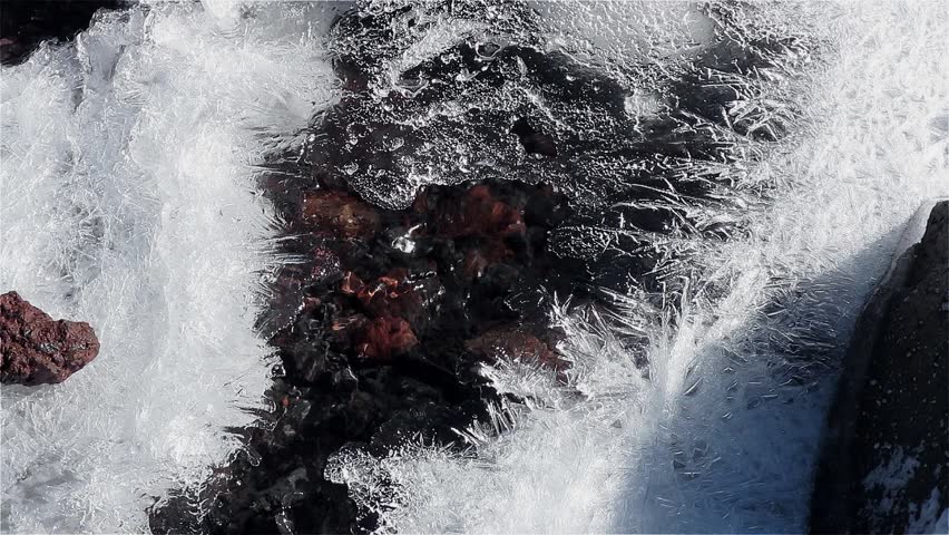 Clear mountain stream flowing in the mountains. Melting ice around the fresh creek in the mountains. Spring in the mountains and the stream begins to melt. Beautiful patterns on melting ice.
