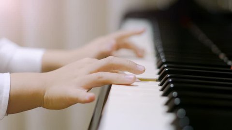 Child playing piano.
Side view of a child playing piano. Close up on piano keys, child hands and fingers.