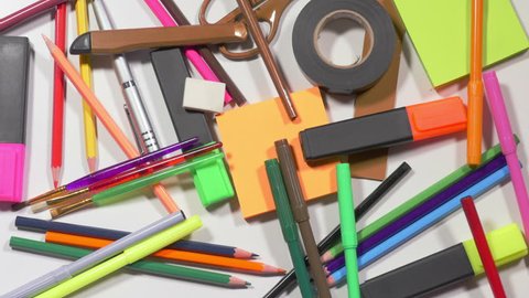 Colorful pencils, markers, scissors, stickers, pen, rulers one by one disappear from pile on table, office supplies, stationery. Close up, stop motion, 4K Ultra HD.