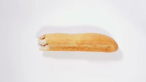 Baguette disappears bite by bite on white background, eating bread, pastries, bakery, wheat bran, healthy food. Close up, stop motion, 4K Ultra HD.