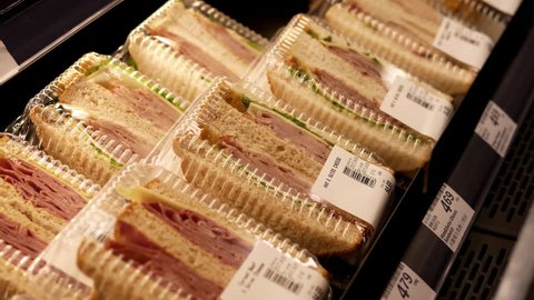 Burnaby, BC, Canada - January 05, 2017 : Woman buying ham and swiss cheese sandwich inside Price Smart foods store with 4k resolution