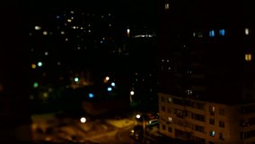 Blurred timelapse clip of night street life. Aerial view of apartment buildings, parking cars and passerby.