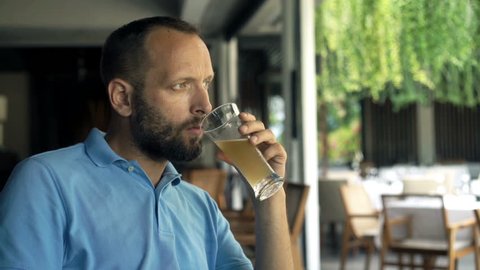 Unhappy, sad man drinking beer in cafe, 4K
