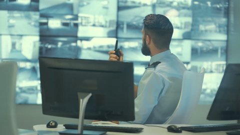 4K Security team watching CCTV video screens in observation control room Dec 2016-UK