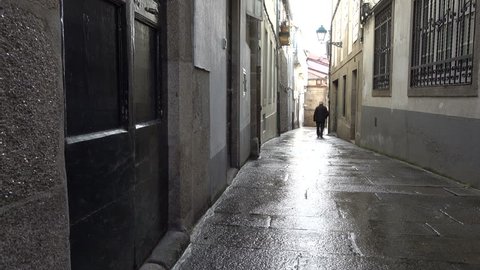 Old man walks in small alley in Santiago de Compostela, Spain, culmination of the Camino de Santiago pilgrimage route
