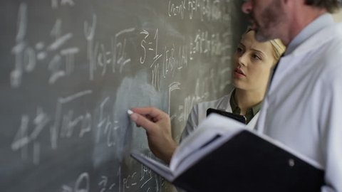 4K Scientists in white coats writing math formulas on blackboard Dec 2016-UK