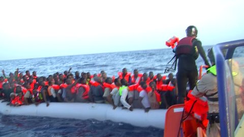 MEDITERRANEAN SEA, SEA/LYBIA-ITALY – OCT 25: Norwegian police of FRONTEX agency, rescues a rubber boat on 2016 mediterranean sea.