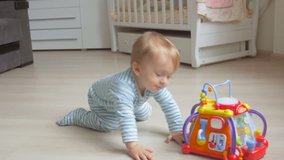 Cute baby boy crawling on floor at living room and taking a toy