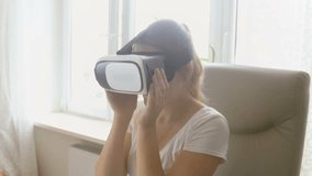 Portrait of young woman watching 360 video in virtual reality headset at home. Footage shot at 4K