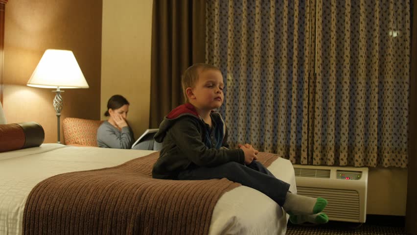 Adorable little boys watching the Television in their hotel room at night with their family