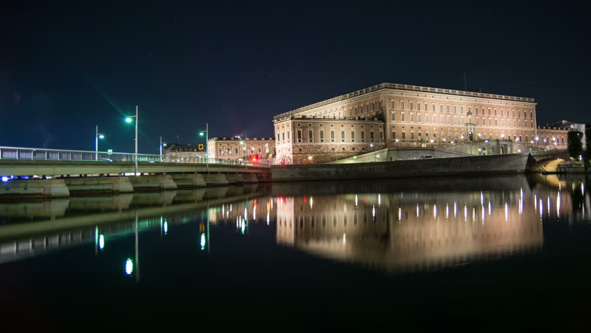 Stockholm Royal Palace at night Time Lapse Tilt. Historical old building reflection in calm water. Bridge with traffic, Stockholm, Sweden