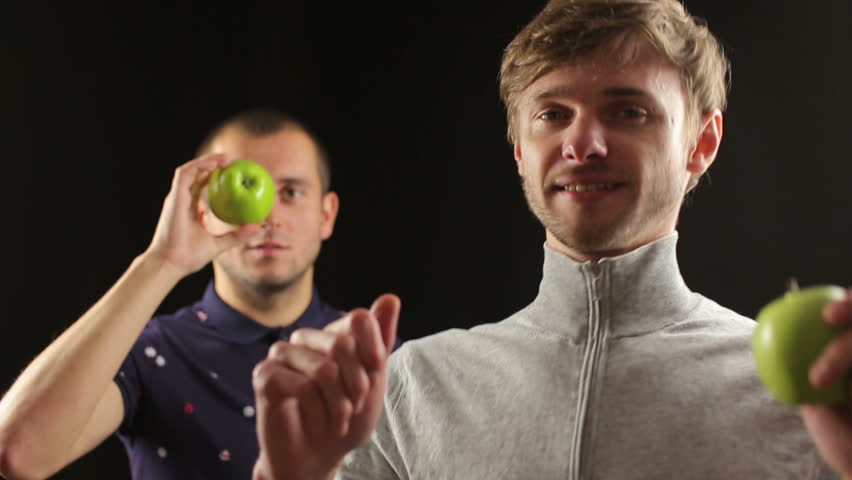 two guys funny dancing holding green apples isolated in black