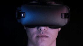 Close-up shot of a young man wearing VR Headset playing virtual reality games. Futuristic hud around him.