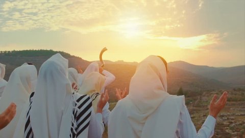 Jewish men pray With Talit and shofar in sunset