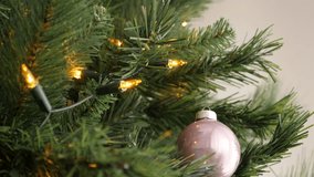 Shiny pink Christmas tree bauble close-up 3840X2160 UHD tilting footage - Reflective New Year decorative ornament hangs on artificial branch slow tilt  2160p 30fps UltraHD video