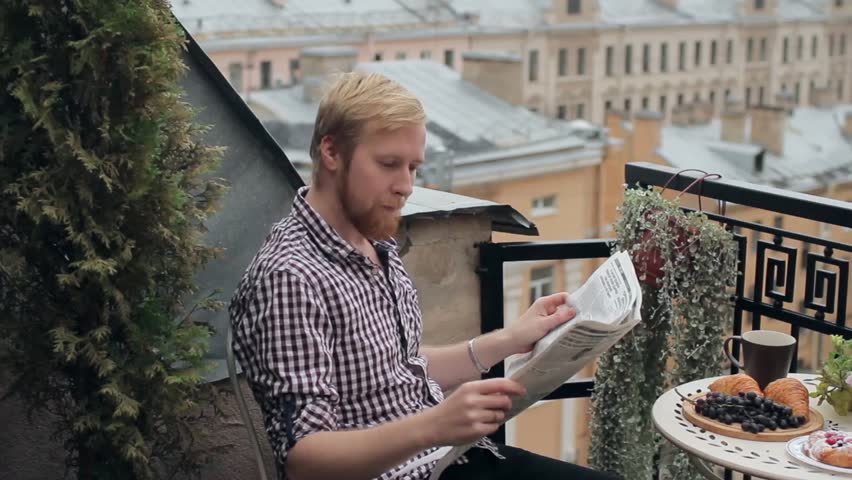 Man Reading a Newspaper on the Balcony Overlooking the City