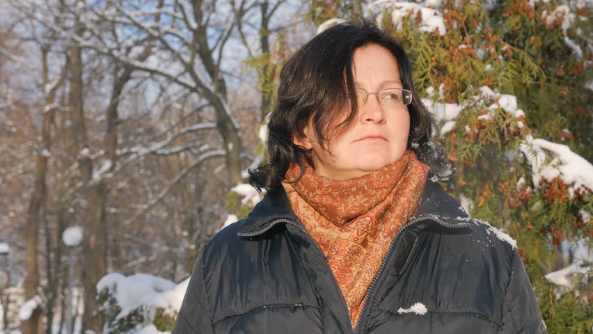 A young woman in a Park with fir on the street, hands touch the branches of trees, examining them. Season winter