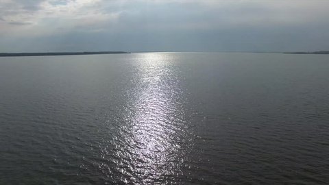 Aerial view of lake, fly over the water, sun reflection on the water