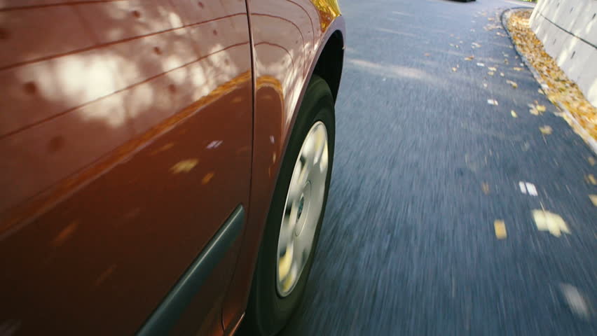 Real scene of front tires driving on highway very fast - red coupe race car driving on freshly posed asphalt on a mountain highway