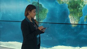4K Businesswoman with tablet looking at large world map graphic on video wall Dec 2016-UK