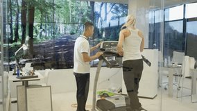 4K Woman with personal trainer using treadmill in modern gym Dec 2016-UK