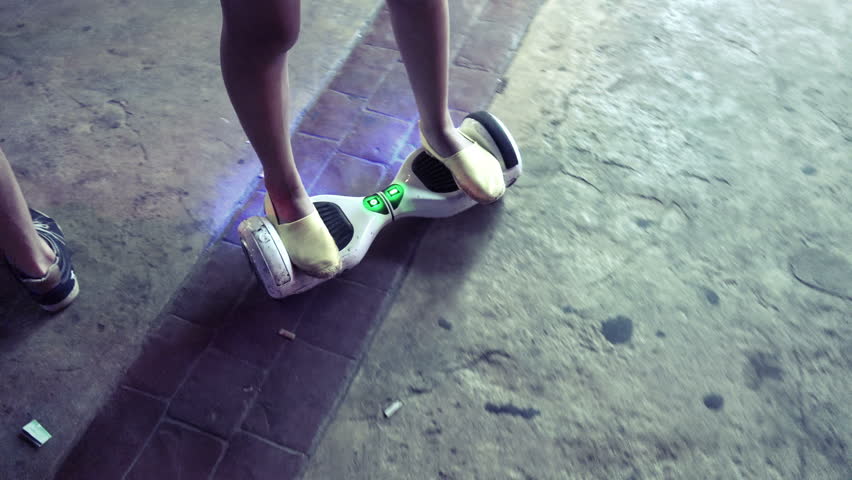Girl ride on electrical scooter hoveboard at night on walkway