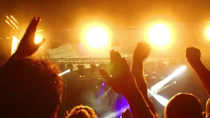 silhouettes of concert crowd in front of bright stage lights, visible noice from high ISO, SLOW MOTION