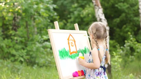 Little girl painting a dream home in the park