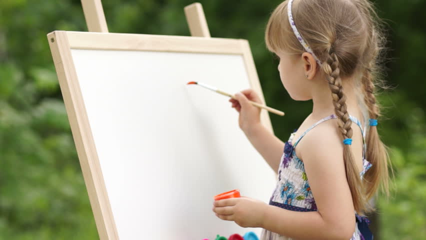 Little girl makes the first brush stroke on a painting