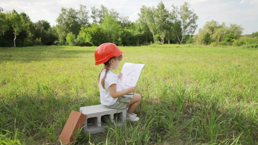 Girl in the field with a drawing of a house. Looking at camera