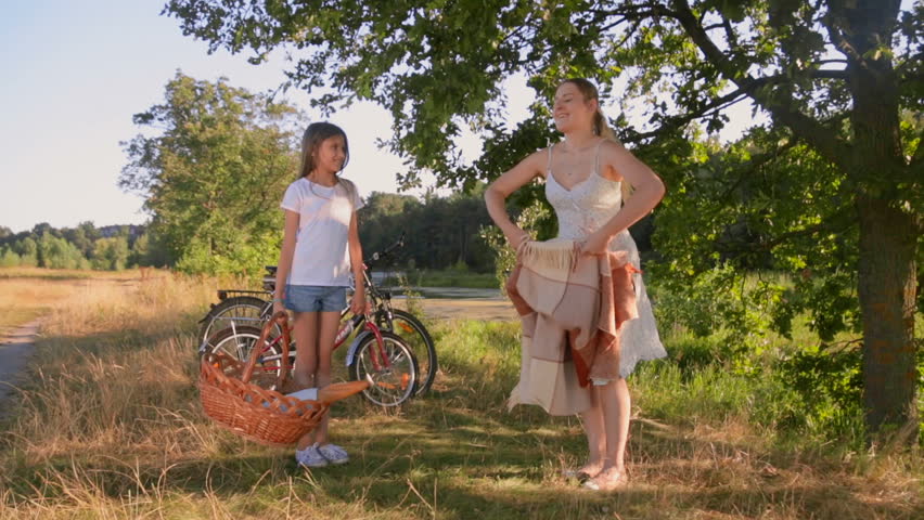 Beautiful young mother having picnic with her daughter next to a lake 