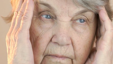 Old woman holding his head with hands due to headache. Face close up