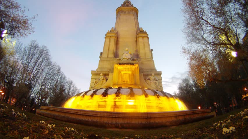 Fountain stands against blue sky at sunset, time lapse