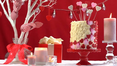 Beautiful St Valentines Day party table with showstopper red, white and pink hearts double layer cake, with white chocolate frosting, short dolly reveal close up.