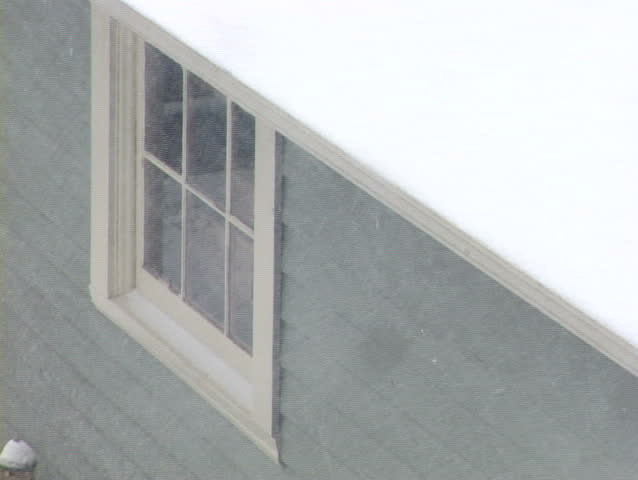 Blizzard in Portland Oregon blows snow furiously off roof top showing window.