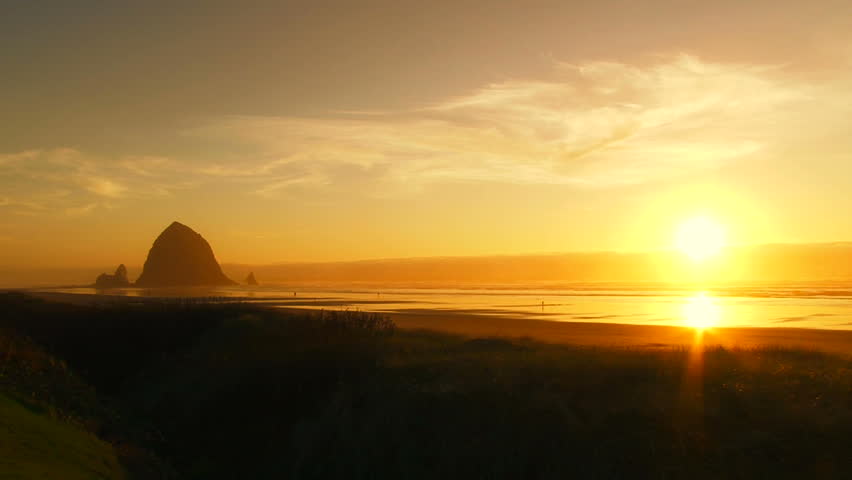 Tilt down revealing sunset at beach in Cannon Beach, Oregon.