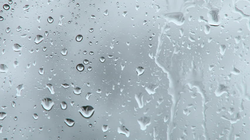 Rain falling on glass during rain storm, close up.