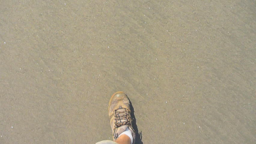 Man hikes on sandy beach point of view.