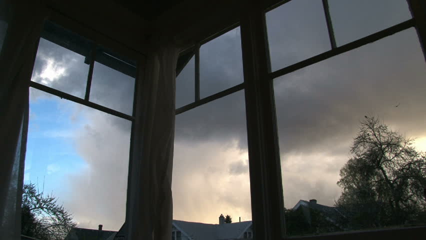 Full sunrise time lapse through old windows in house. Rain clouds develop and