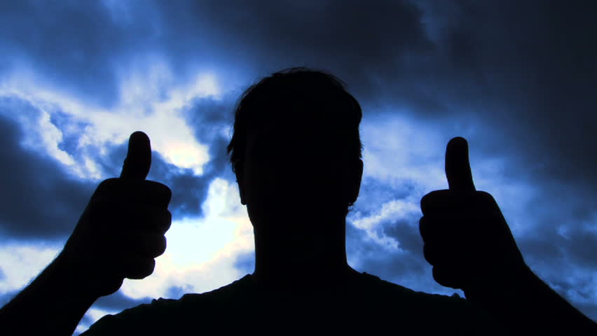 Person silhouetted raises hand into frame to give two thumbs up sign then walks